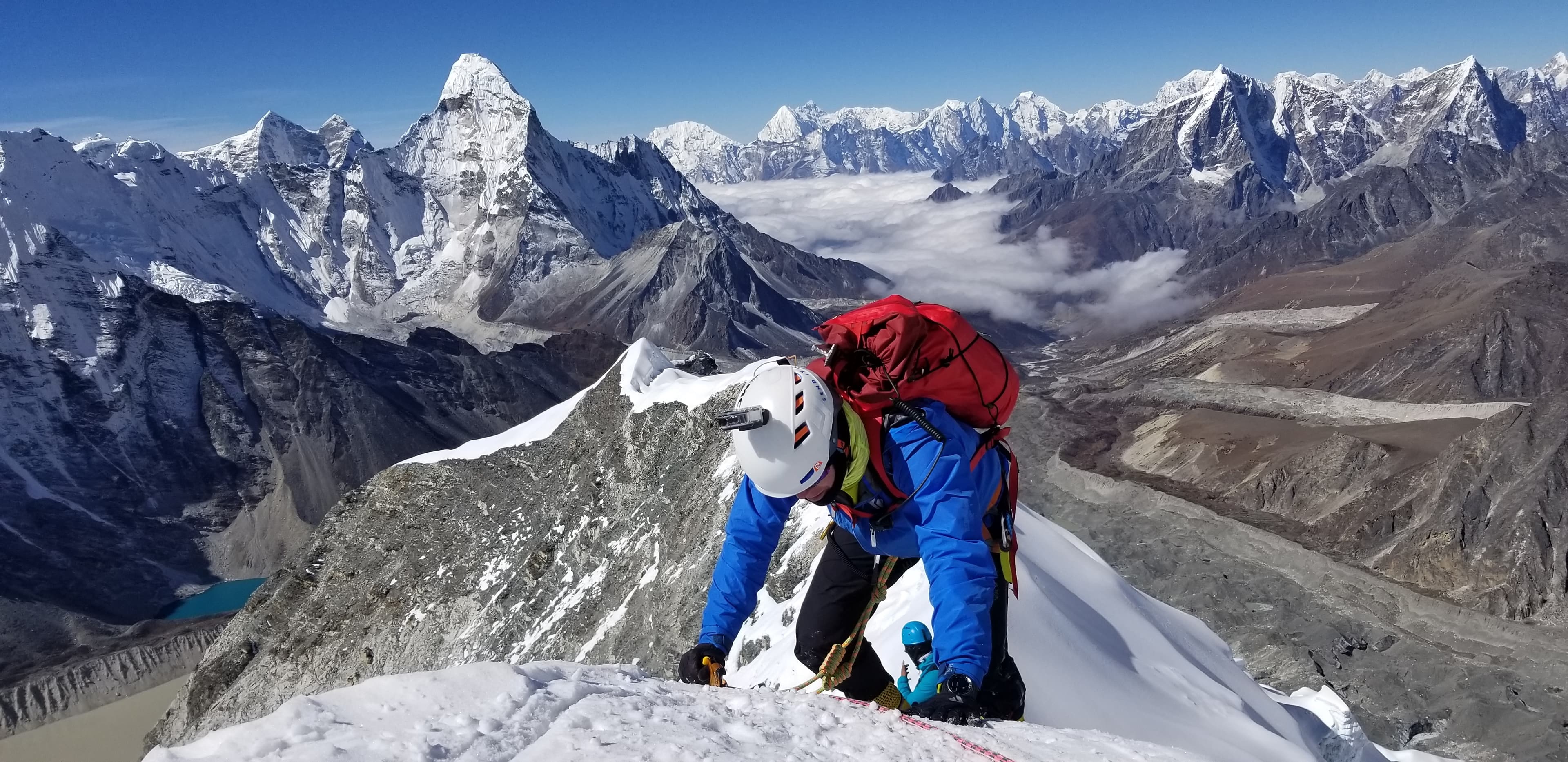 A climber on a snow ridge above the Khumbu valley, Ama Dablam in the distance